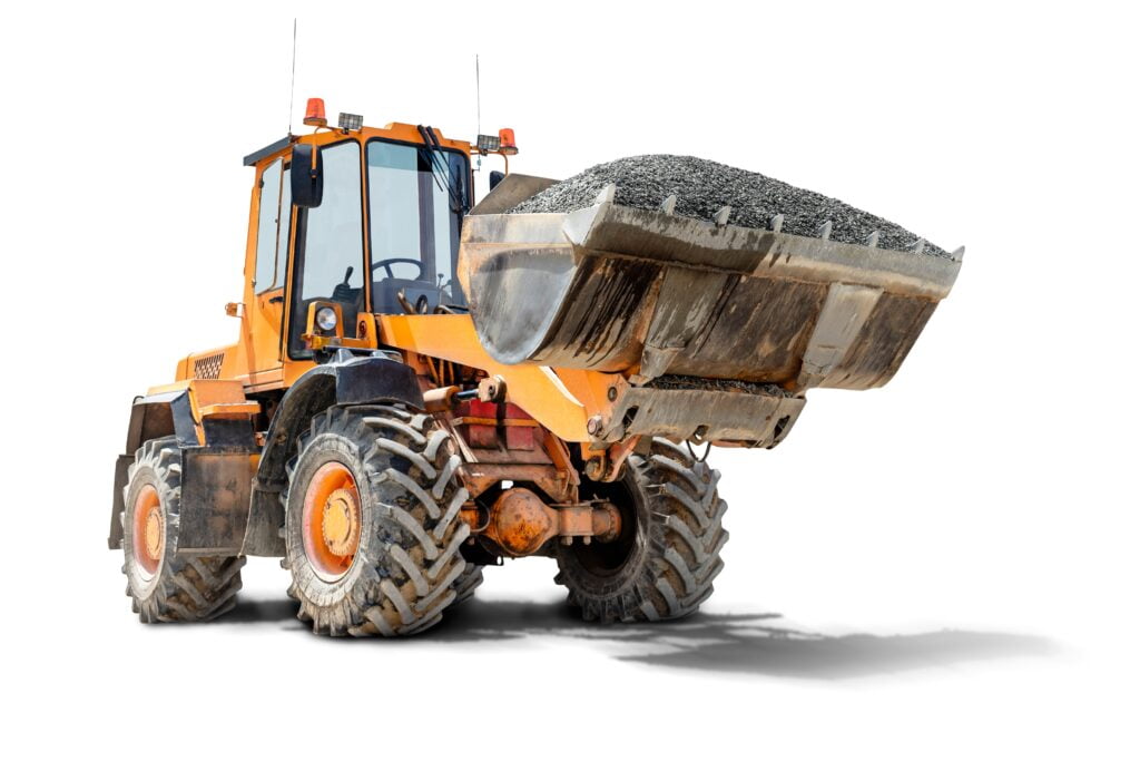 A large front loader transports crushed stone or gravel in a bucket at a construction site.